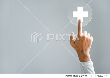 A hand touches a plus icon, emphasizing health, medicine, and insurance. Portrays a protective family business concept. Highlighting hospital access, welfare health service. A hand touches a plus icon, emphasizing health, medicine, and insurance. Portrays a protective family business concept. Highlighting hospital access, welfare health service. 107766283