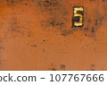Old metal painted texture. Red painted background . Painted surface with rust. The plate with the number 5 on a rusty metal wall. Old uneven iron surface. Perfect for grunge design. 107767666