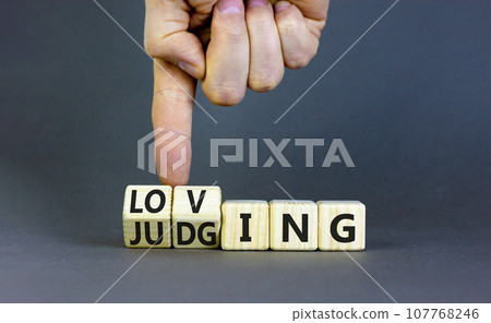 Loving or judging symbol. Concept words Loving or Judging on wooden cubes. Businessman hand. Beautiful grey table grey background. Business loving or judging concept. Copy space. 107768246