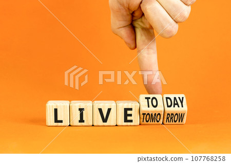 Live today not tomorrow symbol. Businessman turns wooden cubes and changes word Live tomorrow to Live today. Beautiful orange background. Business and live today not tomorrow concept. Copy space. 107768258