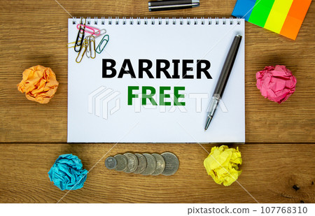 Barrier free symbol. Words 'Barrier free' on white note. Wooden table, colored paper, paper clips, pen, coins. Business, diversity, inclusion, belonging and barrier free concept. Copy space. 107768310