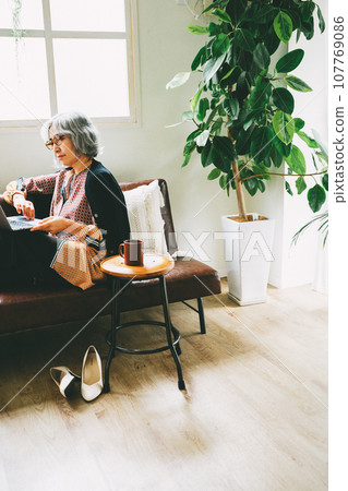 Senior woman relaxing on the sofa and staring at a PC 107769086