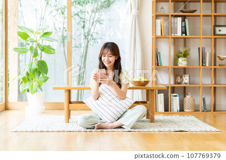 Young woman looking at her smartphone in the living room 107769379