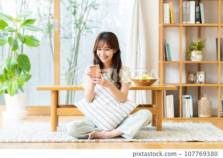 Young woman looking at her smartphone in the living room 107769380