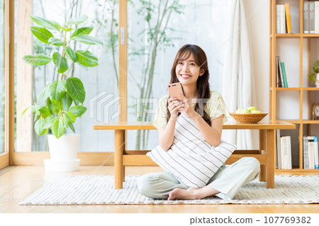 Young woman looking at her smartphone in the living room 107769382
