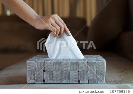 Close up of hand female picking a white tissue paper from gray box. Close up of hand female picking a white tissue paper from gray box. 107769556