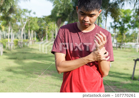 Closeup of male arms holding her painful wrist because exercise - workout concept. Closeup of male arms holding her painful wrist because exercise - workout concept. 107770261