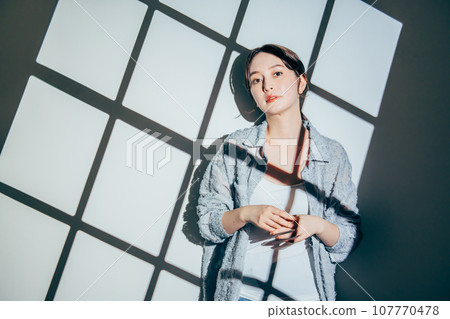 A young woman standing by the window A young woman standing by the window 107770478