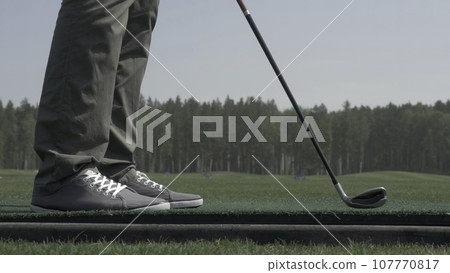 Golfer Hitting Ball with Club on Beautiful Golf Course. Golfer hits an fairway shot towards the club house. Man hitting driver on a golf course in the sun. Professional male golf player 107770817