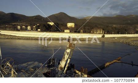 Close-up of old and destroyed ship trunk and gull sitting on a rusty pipe against the sunset sky. Shot. Marine landscapes Close-up of old and destroyed ship trunk and gull sitting on a rusty pipe against the sunset sky. Shot. Marine landscapes 107770894