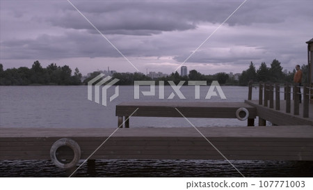 Side view of a handsome man in walking at the lake pier. Silhouette of man on the old wooden bridge natural landscape sunny lake background Side view of a handsome man in walking at the lake pier. Silhouette of man on the old wooden bridge natural landscape sunny lake background 107771003