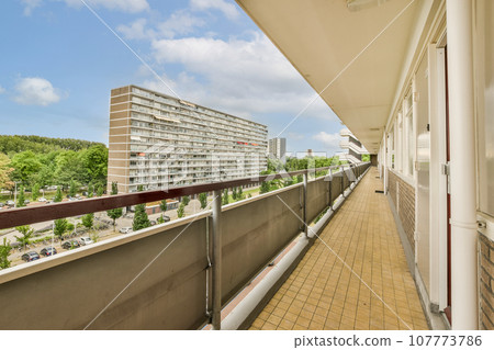 a balcony with some buildings in the background and blue skies overhead over the cityscaing area on the right side 107773786