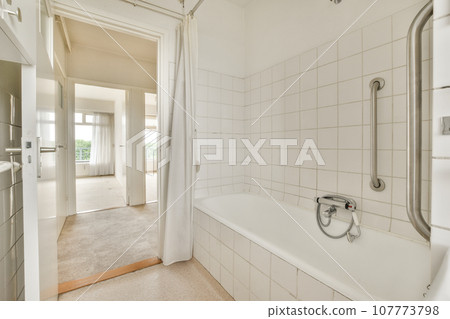 a bathroom with a bathtub and shower in the corner, taken from the inside looking into the room through the door a bathroom with a bathtub and shower in the corner, taken from the inside looking into the room through the door 107773798