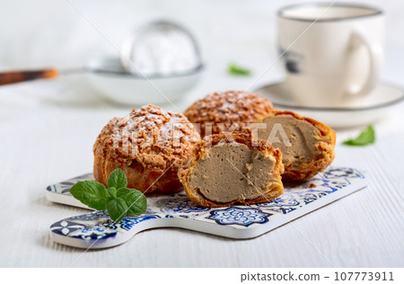 Custard cakes (choux) with coffee cream. 107773911