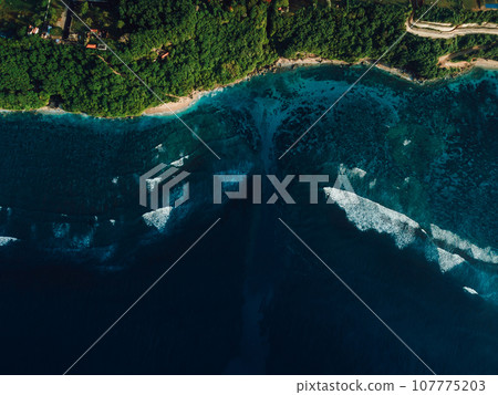 Aerial view of coastline with ocean waves and powerful current canal in Bali. Green bowl beach Aerial view of coastline with ocean waves and powerful current canal in Bali. Green bowl beach 107775203
