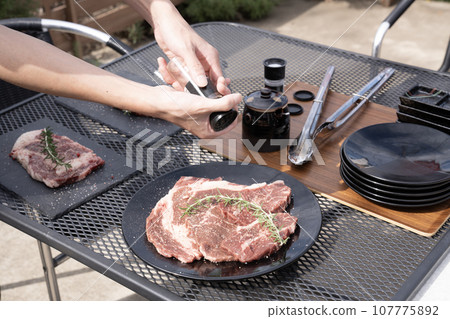 Hand of a man salting beef 107775892