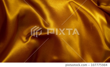 Smooth Elegant Golden Satin Cloth, Close-up. Texture of flying fabric. 107775984