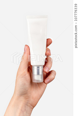 Plastic cream tube, white blank package in hand isolated on white Plastic cream tube, white blank package in hand isolated on white 107776339