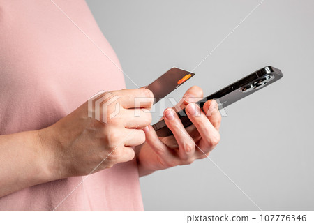 Berlin, Germany October 6 2023 Hands holding mobile phone and bank card, paying online with smartphone 107776346