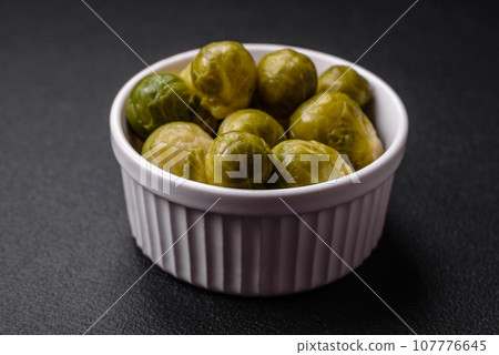 Delicious boiled Brussels sprouts on a ceramic plate on a dark concrete background 107776645