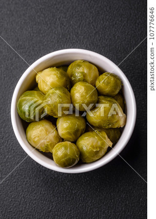 Delicious boiled Brussels sprouts on a ceramic plate on a dark concrete background 107776646