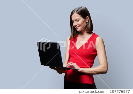 Young business woman with laptop on grey studio background 107776977