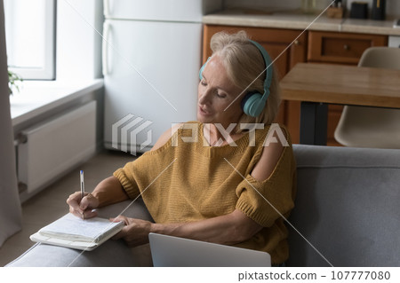 Focused mature 50s student woman watching online training course 107777080