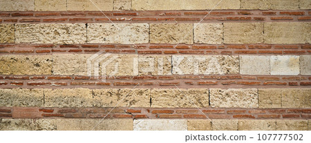 Sturdy yellow and beige cut stone brick wall, seamless lined up 107777502