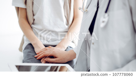 Doctor and child patient. The physician is holding tablet computer and reassuring a boy. The concept of ideal health in medicine 107778060