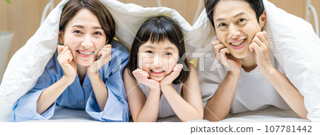 Young friendly family getting into bed Young friendly family getting into bed 107781442