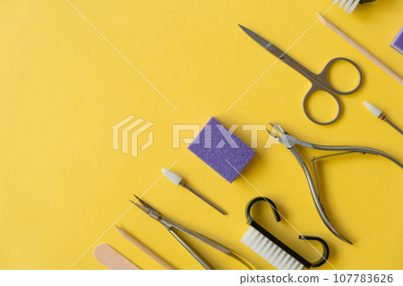 Professional manicure tools on yellow background. Manicure set. Top view. Cuticle pusher, cuticle trimmer and purpose scissor. Set of manicure and pedicure tools and cosmetics with space Professional manicure tools on yellow background. Manicure set. Top view. Cuticle pusher, cuticle trimmer and purpose scissor. Set of manicure and pedicure tools and cosmetics with space 107783626