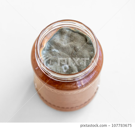 Open jar with sweet jam and mold on a white background. Mold in a jar of raspberry jam. Hazardous to health. Open jar with sweet jam and mold on a white background. Mold in a jar of raspberry jam. Hazardous to health. 107783675