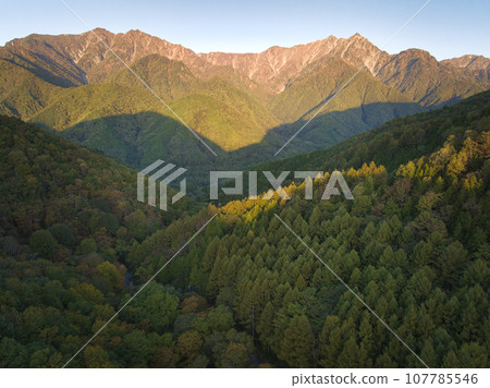 Mt. Jigatake and Mt. Kashimayarigatake bathed in the morning sun as seen from Kurosawa Plateau and the forest of autumn leaves in Omachi City, Nagano Prefecture (aerial shot by drone) Mt. Jigatake and Mt. Kashimayarigatake bathed in the morning sun as seen from Kurosawa Plateau and the forest of autumn leaves in Omachi City, Nagano Prefecture (aerial shot by drone) 107785546