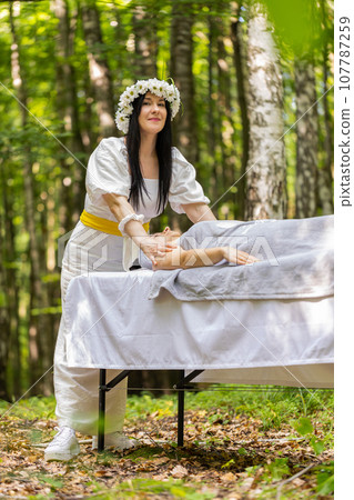 Therapist female doctor making woman relaxing spa face massage with hands outdoors in the forest 107787259
