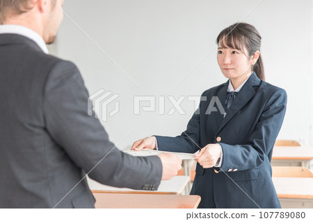 Teachers handing out diplomas and students receiving them at the graduation ceremony (high school girls, high school students, junior high school students) 107789080
