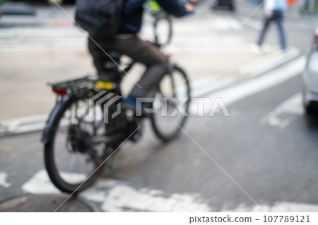 Defocused food delivery service bike rider on city street Defocused food delivery service bike rider on city street 107789121