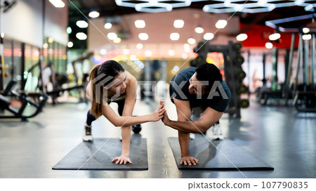 Athletic Sportsman and Sportswoman Doing Push Ups Together at Fitness Gym 107790835
