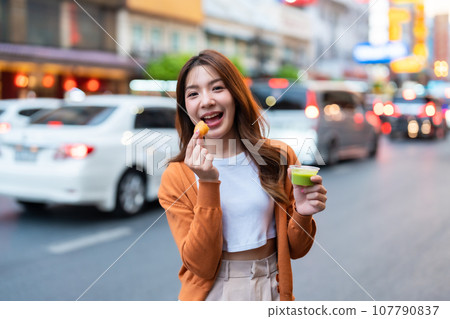 Young Asian tourists standing and eating Thai desserts 107790837