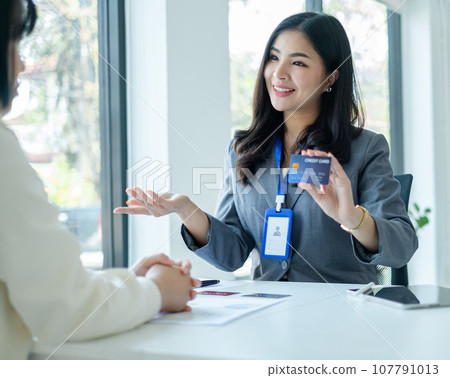 Asian business customer service representatives work and smile serve sell credit card to customers. choosing insurance plan in office Asian business customer service representatives work and smile serve sell credit card to customers. choosing insurance plan in office 107791013