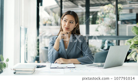 Asian businesswoman sit at their desks and calculate financial graphs showing results about their investments, planning a successful business growth process Asian businesswoman sit at their desks and calculate financial graphs showing results about their investments, planning a successful business growth process 107791014