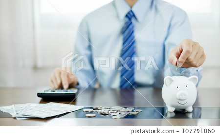 Hand putting coin into piggy bank. Saving money with coins steps into a successful growing business, and saves it for retirement. Retirement Savings concept 107791060
