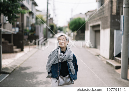 一位優雅的日本女性，頭髮灰白，走在安靜的住宅區 107791341