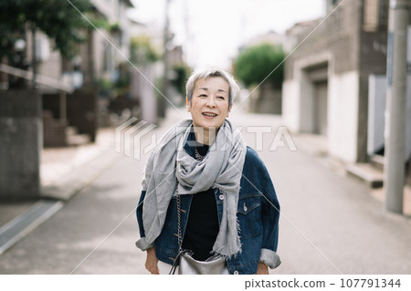一位優雅的日本女性，頭髮灰白，走在安靜的住宅區 107791344