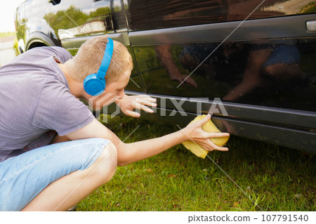 Teenager Boy Washing and Cleaning car in front of his House Teenager Boy Washing and Cleaning car in front of his House 107791540