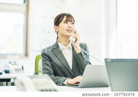 Woman answering the phone in the office Woman answering the phone in the office 107792078