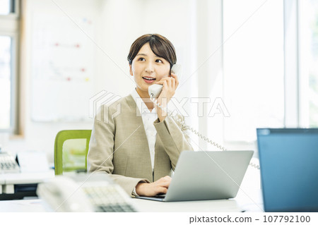 Woman answering the phone in the office 107792100