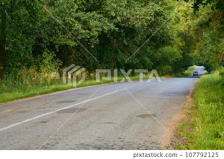 Travelling by car. Asphalt road among summer fields of green plantings Travelling by car. Asphalt road among summer fields of green plantings 107792125