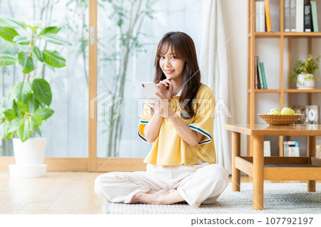 Young woman looking at her smartphone in the living room 107792197