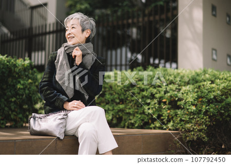 一位優雅的日本女商人,頭髮灰白,坐在街角 一位優雅的日本女商人,頭髮灰白,坐在街角 107792450