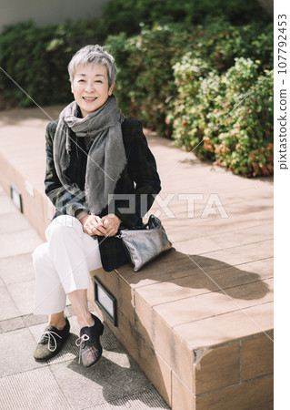 一位優雅的日本女商人，頭髮灰白，坐在街角 107792453